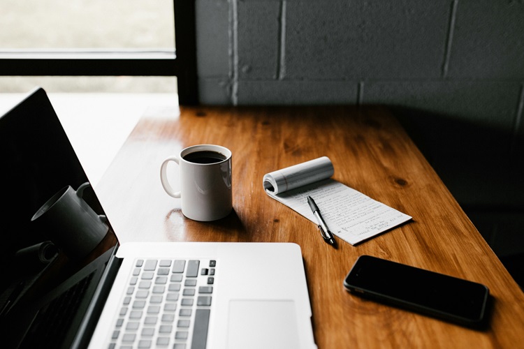 A desk with a laptop, a written plan and a pen
